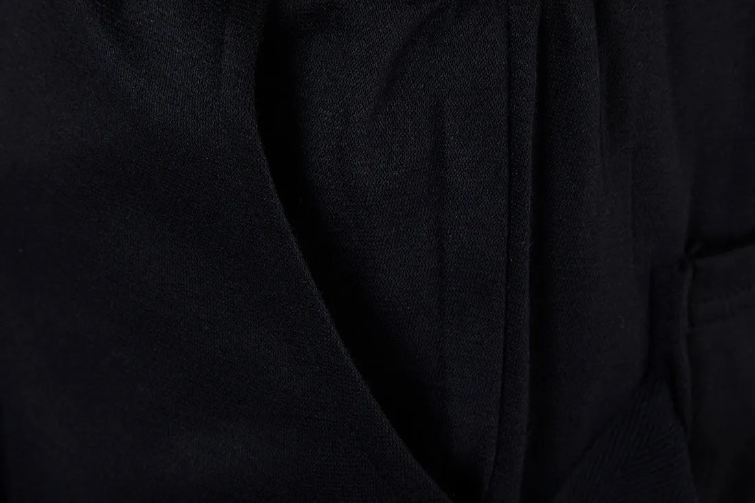 Men's black low crotch cross trousers with tapered cone leg and small hem on a plain background