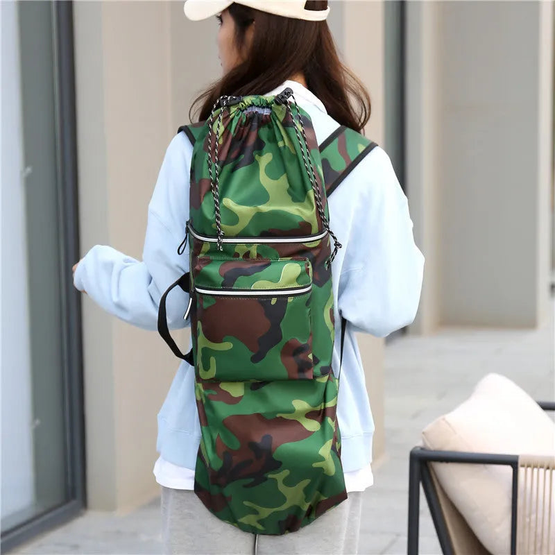 Roll-up skateboard bag in black nylon with an adjustable shoulder strap, shown carrying a skateboard.
