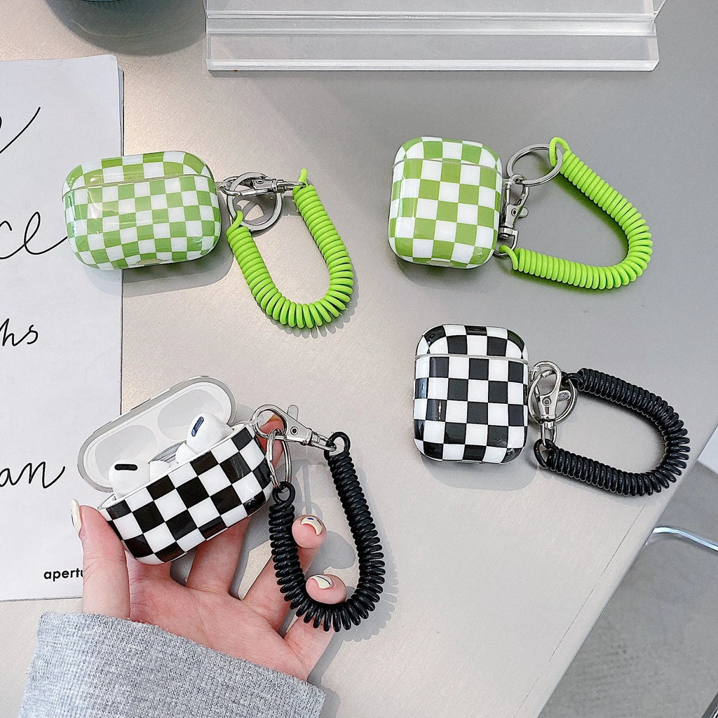 Black and green checkerboard pattern TPU protective case sleeves for Apple AirPods, one with a smiley face lanyard attached.