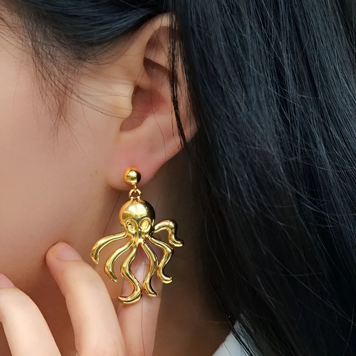 Gold stainless steel octopus drop earrings on a neutral background