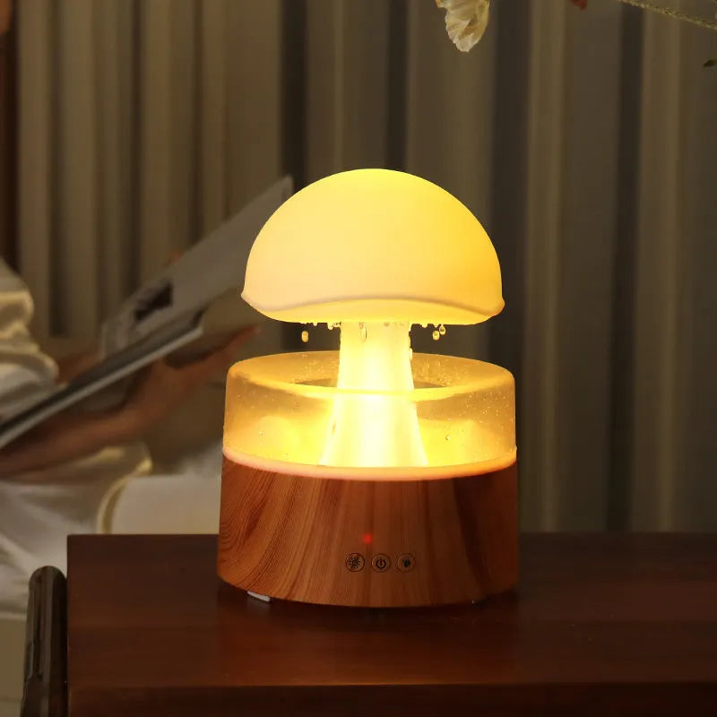 White plastic rain cloud humidifier with mist and coloured night light on a wooden surface