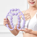 A pink manual leg massager roller with twelve wheels and black ring clips for securing to the leg.