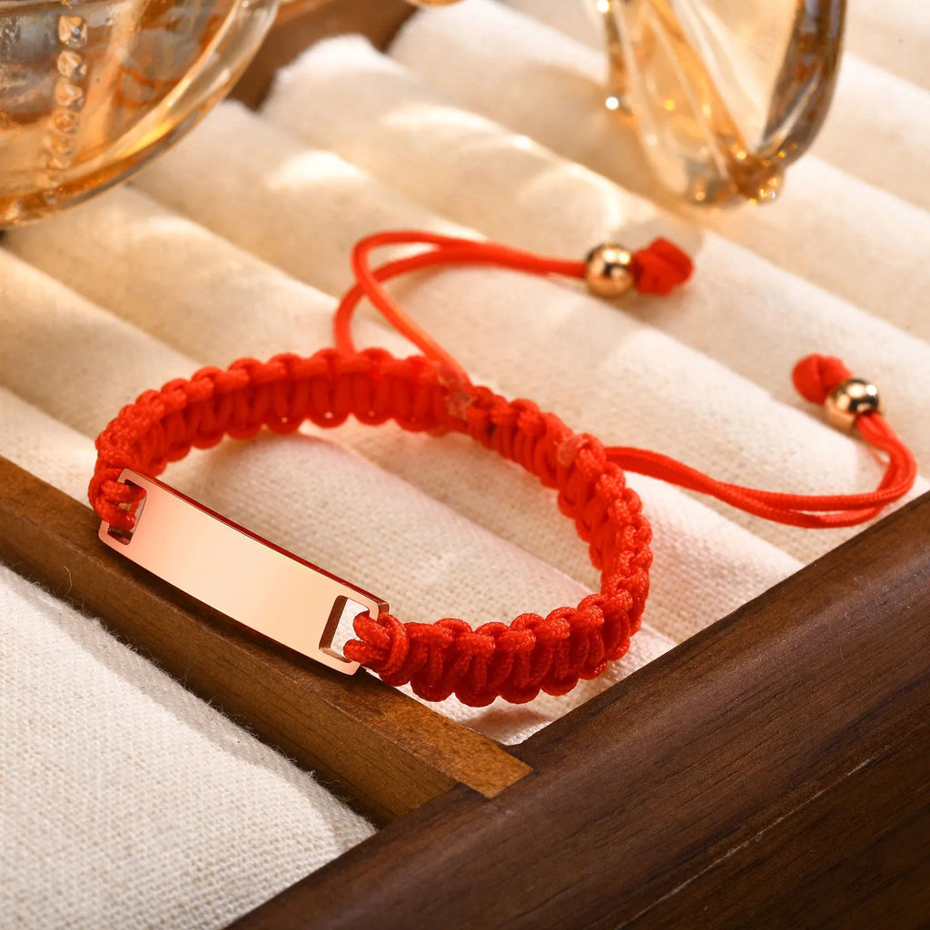 Stainless steel curved brand red nylon rope woven children's bracelet in rose gold on a white background