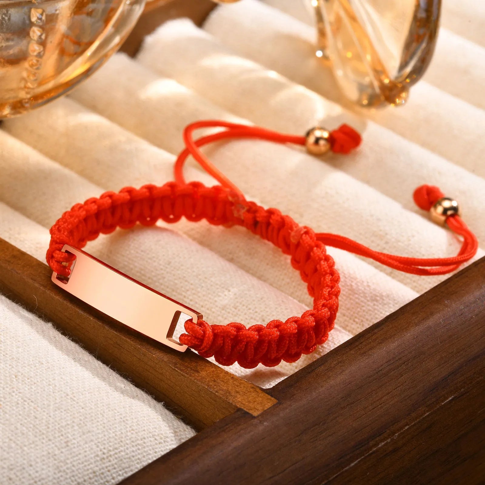 Stainless steel curved brand red nylon rope woven children's bracelet in rose gold on a white background