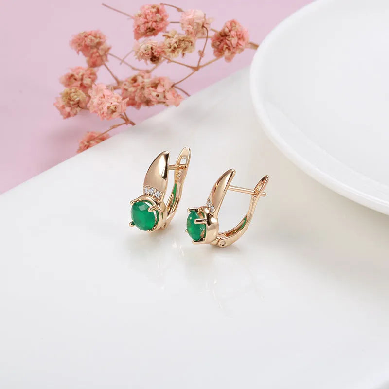 Rose gold plated copper stud earrings with emerald green zircon stone in U-shaped retro design on white background
