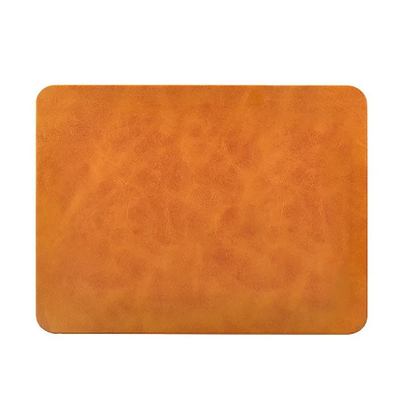 Brown leather-texture wireless charging mouse pad with a phone placed on it charging, on a wooden desk.