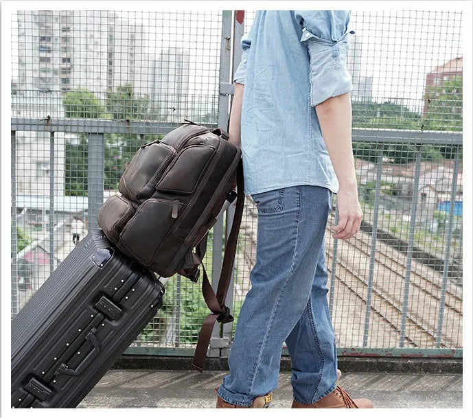 Dark brown genuine leather men's backpack open to show 17-inch laptop compartment and internal organiser pockets.