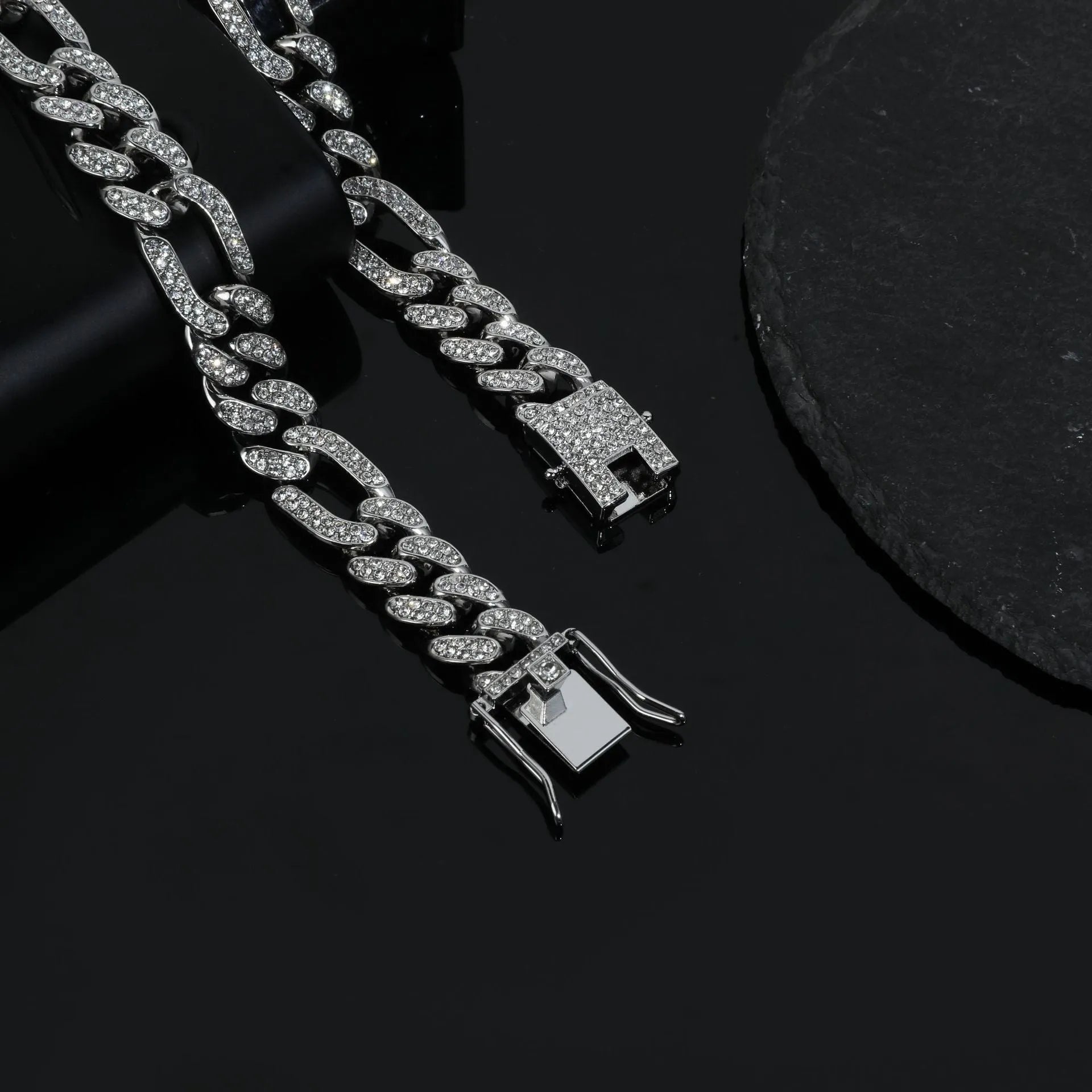 Rap style figaro chain necklace with geometric rhinestone pendant in silver colour on a plain background