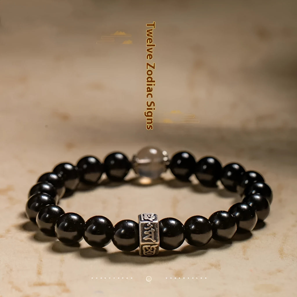 Obsidian bracelet with 8mm beads and a Tibetan zodiac charm on a wrist.