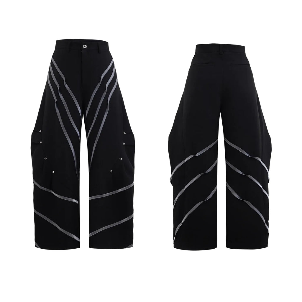 Men's black trousers with metal rivet pleats and a three-dimensional tailored cut.