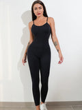 A woman wearing a black sleeveless unitard jumpsuit with spaghetti straps, showing the one-piece design and tummy control panel.