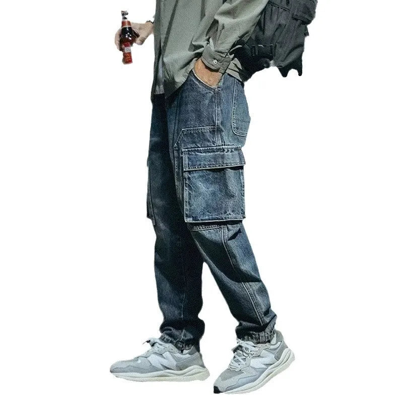 Blue men's loose straight-leg stretch denim trousers on a hanger, showing zip fly placket detail.