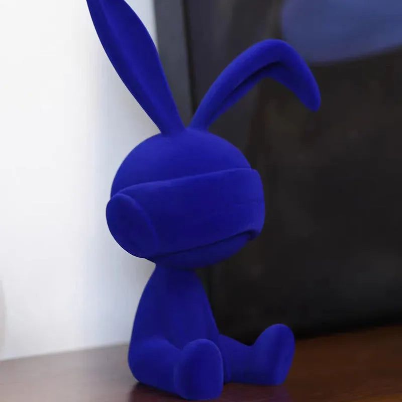 Green suede blindfold rabbit resin table ornament on a wooden surface.