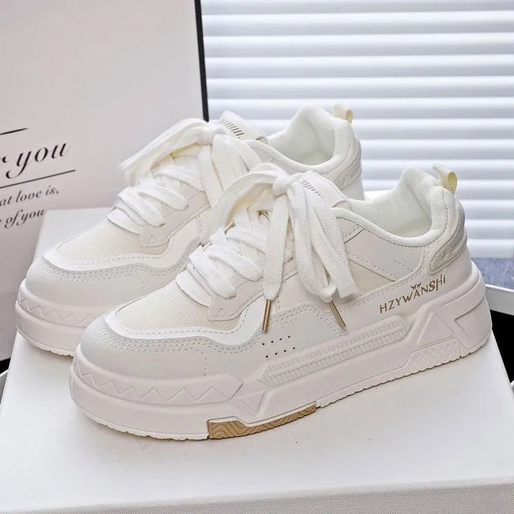Children's beige platform trainers with cross-strap design over laces and a thick rubber sole.