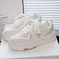 Children's beige platform trainers with cross-strap design over laces and a thick rubber sole.