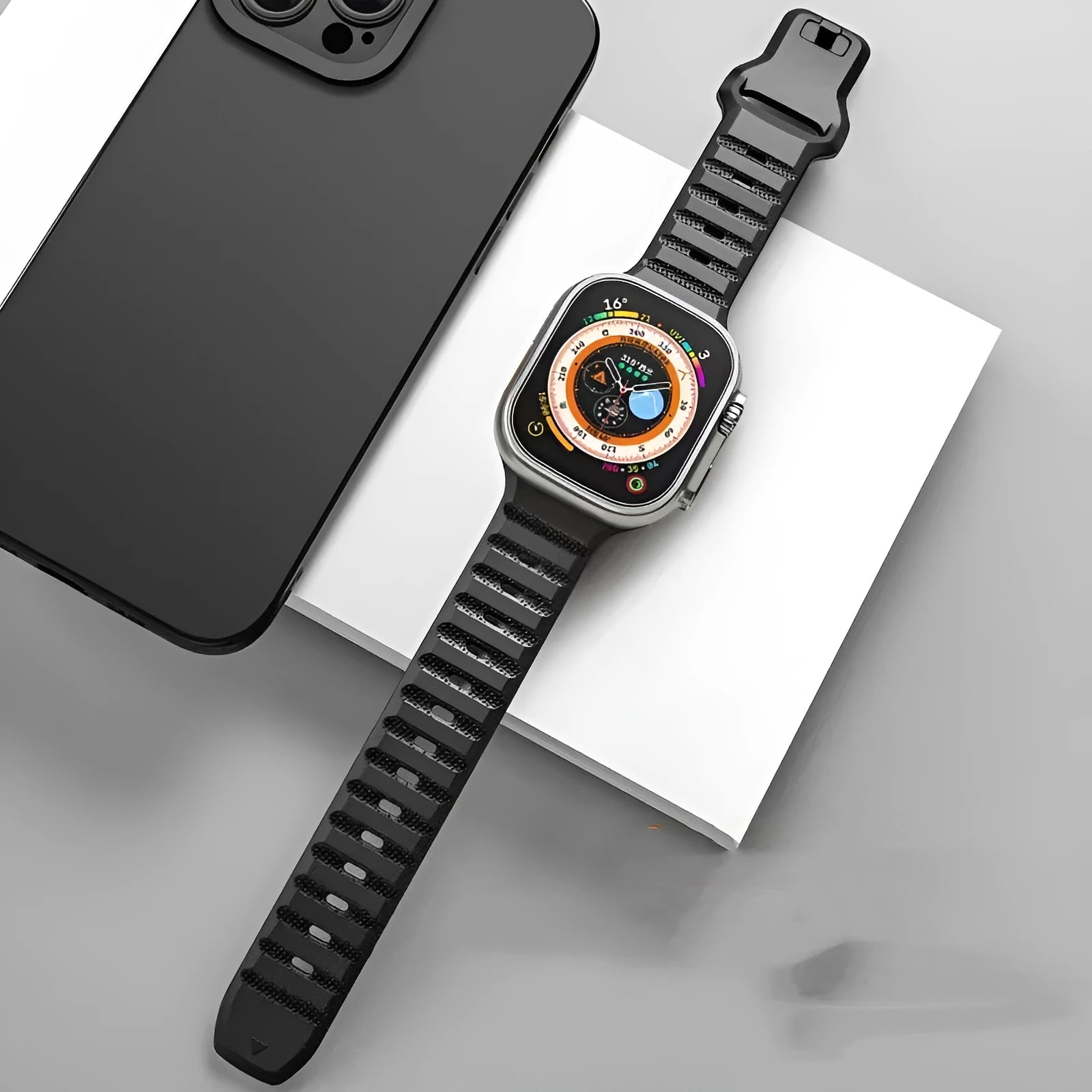 Black fluoro rubber Apple Watch strap with T-buckle closure shown detached from watch.