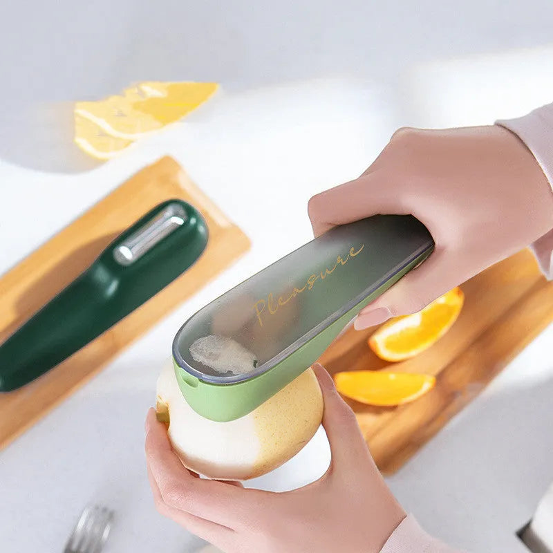 Dark green kitchen peeler with storage tube and stainless steel blade on a worktop.