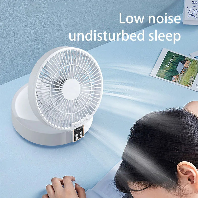White portable folding electric fan with remote control and warm night light on a desk.