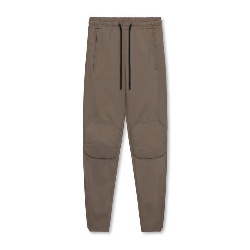 Men's loose grey fitness pants with ankle-tied cuffs laid flat, showing quick-dry polyester fabric.