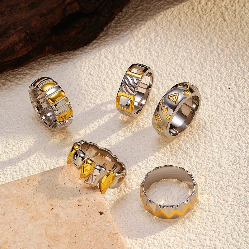 Gold and silver two-tone geometric cross stainless steel ring on a light background showing texture and electroplated finish