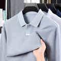 Men's loose fit cotton polo shirt in grey with lapel collar and long sleeves on a mannequin.