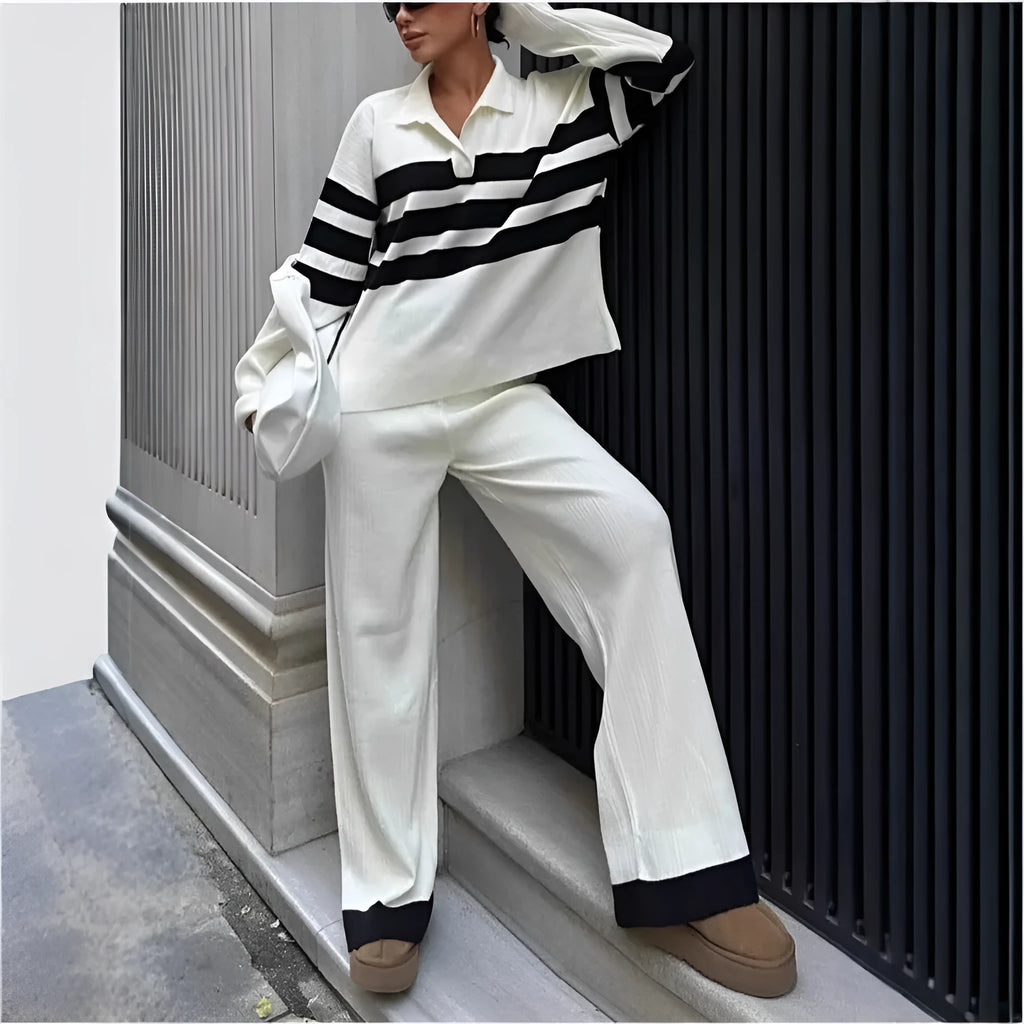 Women's black knitted polo shirt with white stripes and matching trousers laid flat.