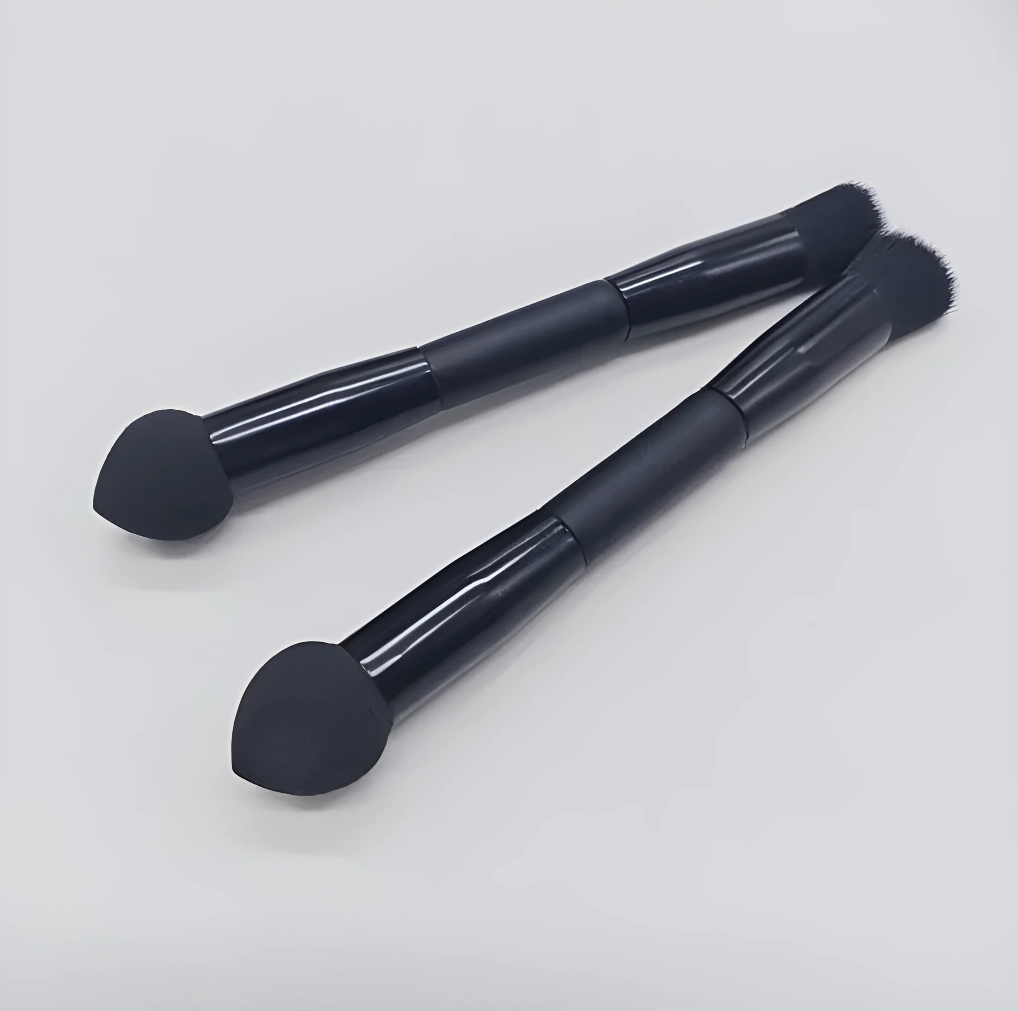 Elegant black double-headed makeup brush with a synthetic fibre brush and a miter sponge on a wooden handle.