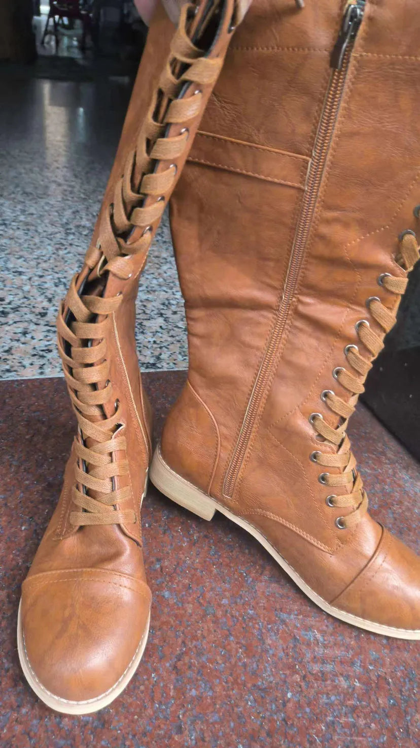 Women's black fashion boots with a cross strap design and side zip closure.