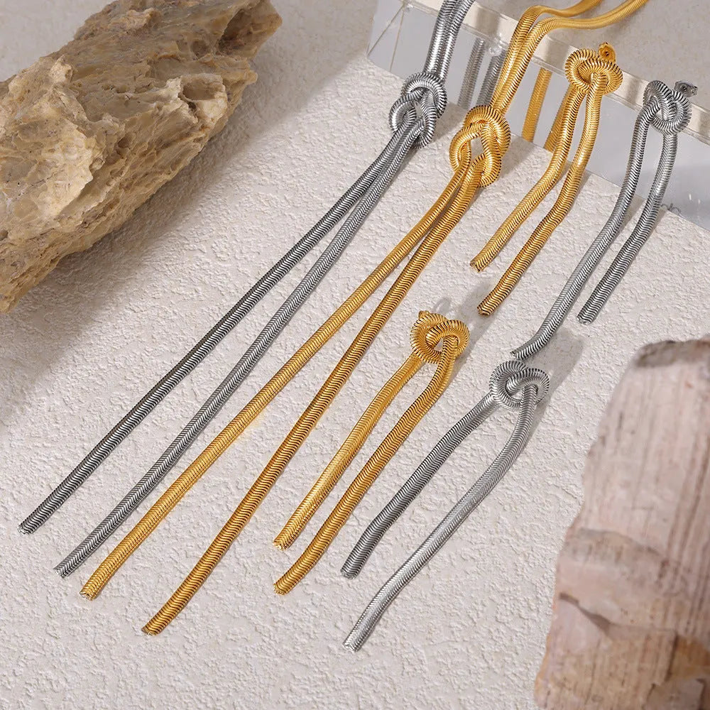 Gold titanium steel knotted tassel necklace and matching earrings set on white background
