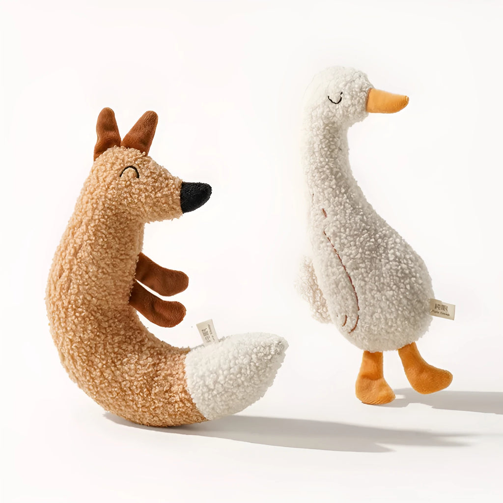 Red fox-shaped and yellow duckling-shaped plush dog toys on a plain background.