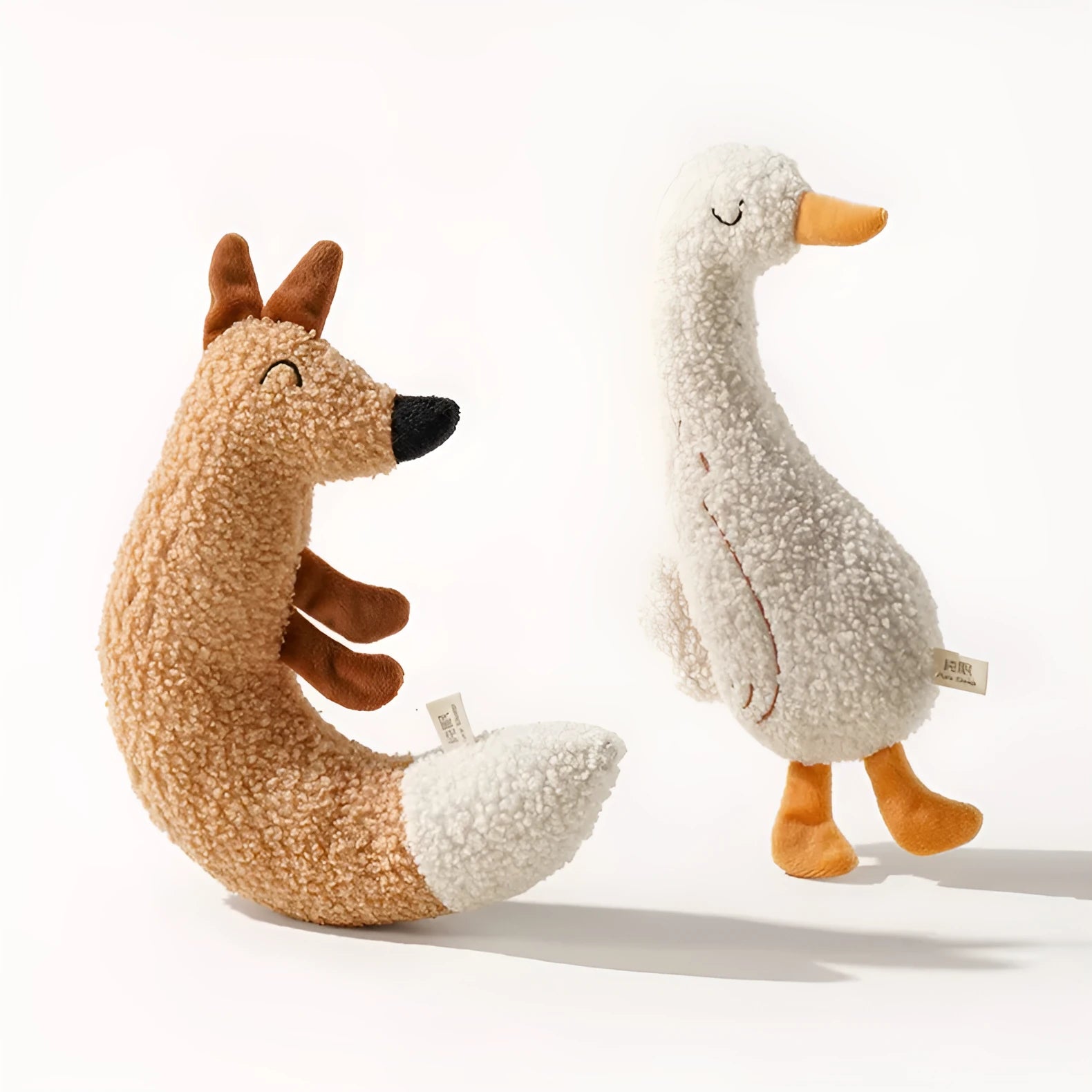 Red fox-shaped and yellow duckling-shaped plush dog toys on a plain background.