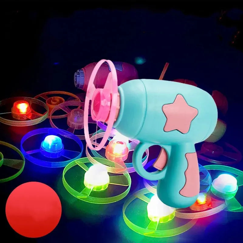Blue plastic flying saucer launcher toy with LED-lit discs on a yellow target board.