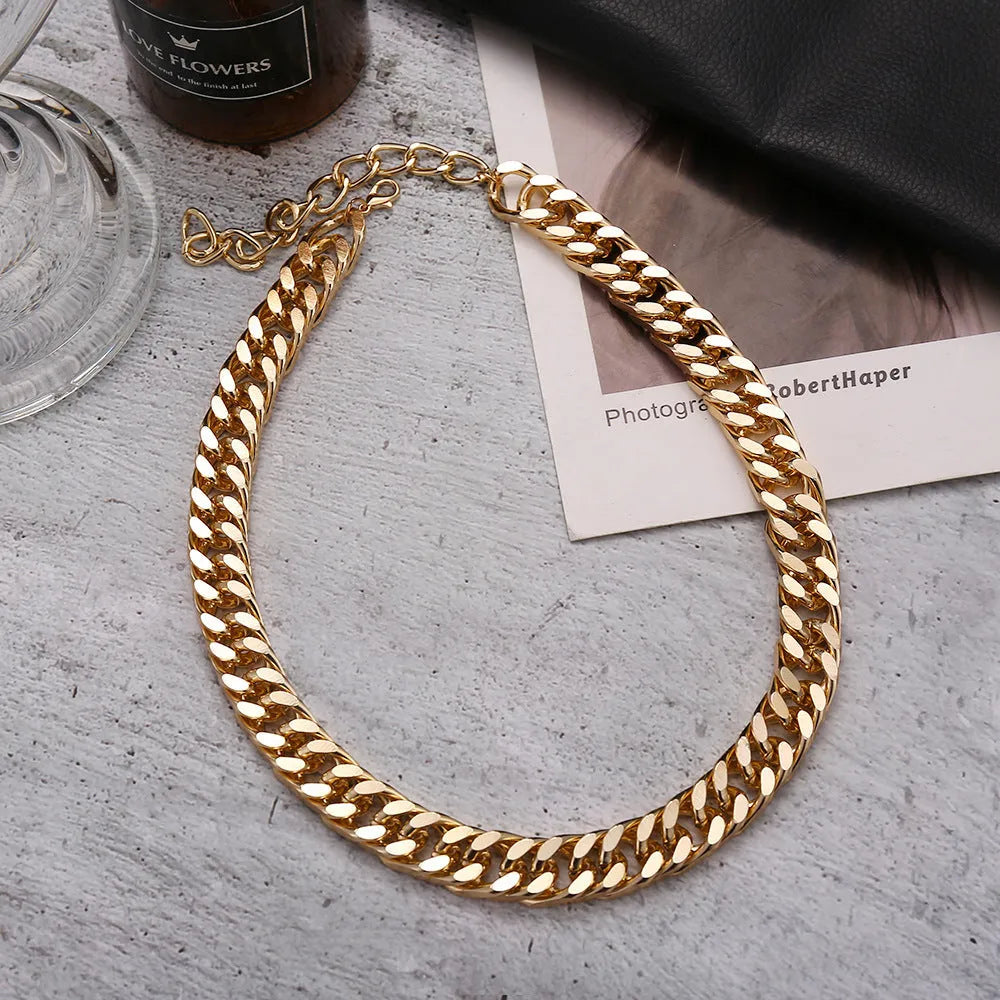 Gold electroplated women's necklace with thick chain and teardrop pendant on a grey background.