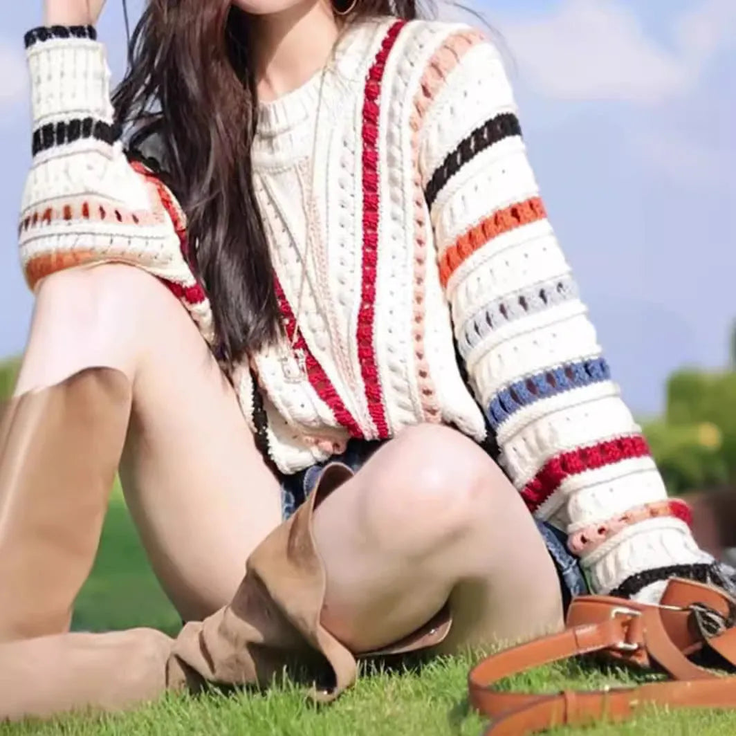 Retro rainbow striped hollow pullover sweater with batwing sleeves on a hanger.