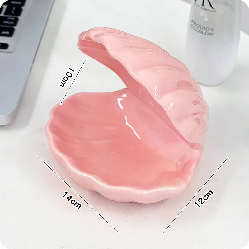 White and pink porcelain shell-shaped tray with integrated yellow LED night light on a wooden table.