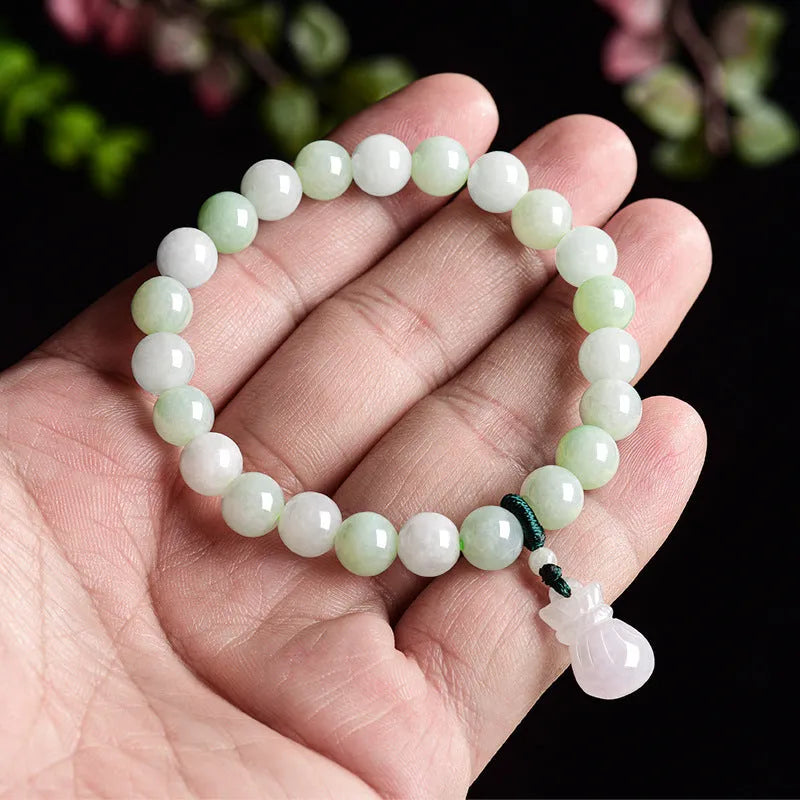 Close-up of an 8mm floral carved jade bracelet on a wrist.