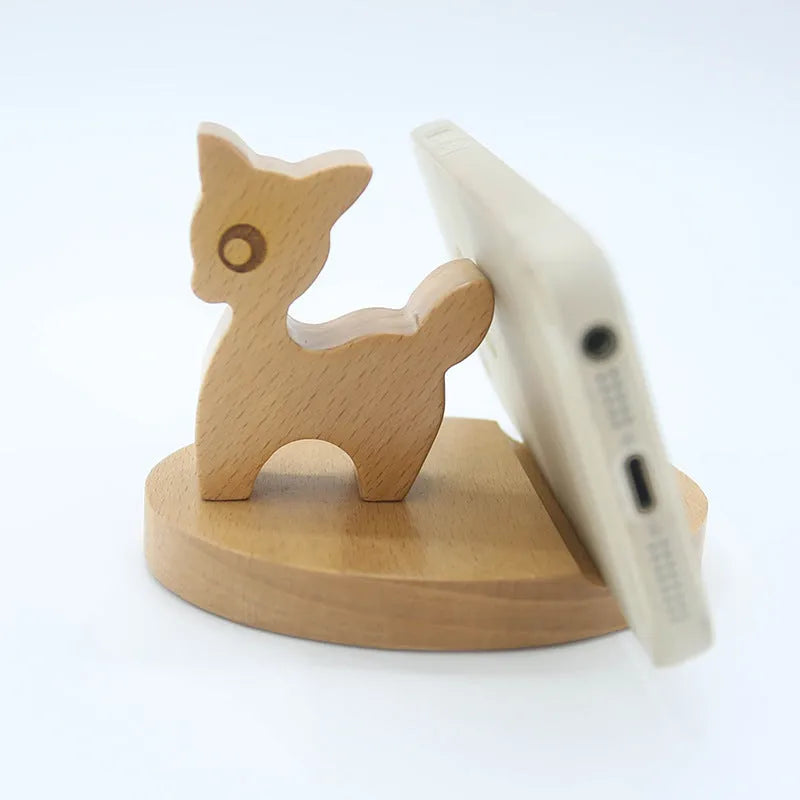 Solid beech wood phone stand with a decorative resin puppy figurine, holding a mobile phone at an angle with a charging cable threaded through the back.