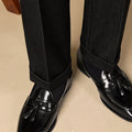 Men's black polished leather tassel loafers with rubber sole, shown from the side.