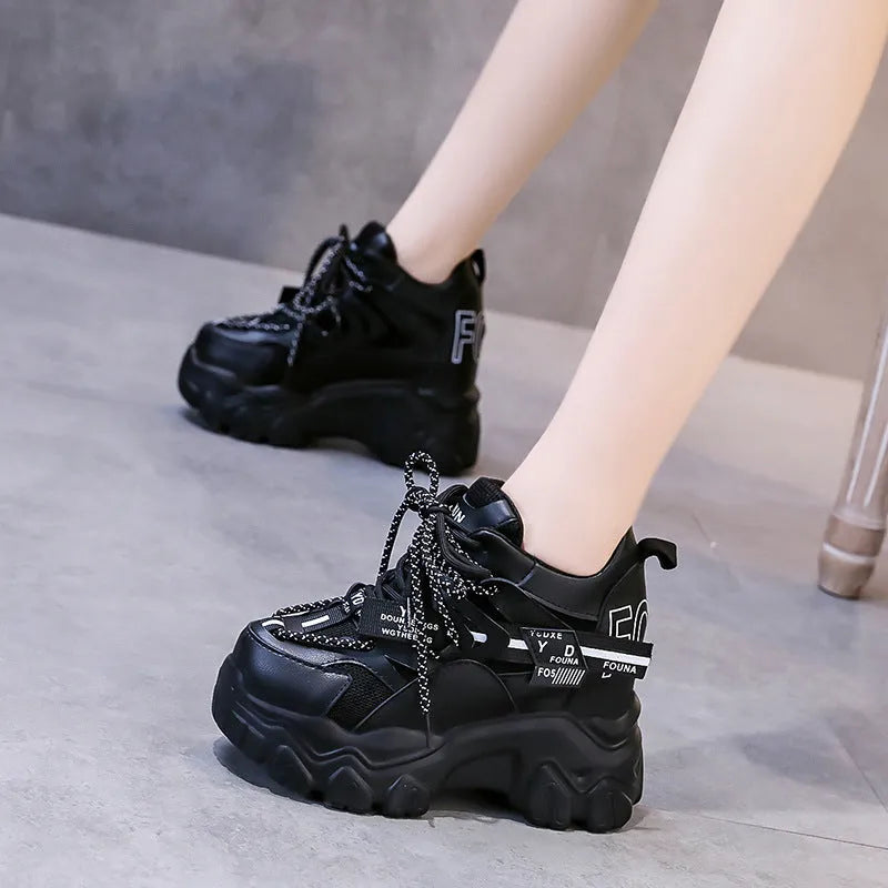 Women's white and black platform sports shoes with cross strap and rubber sole.