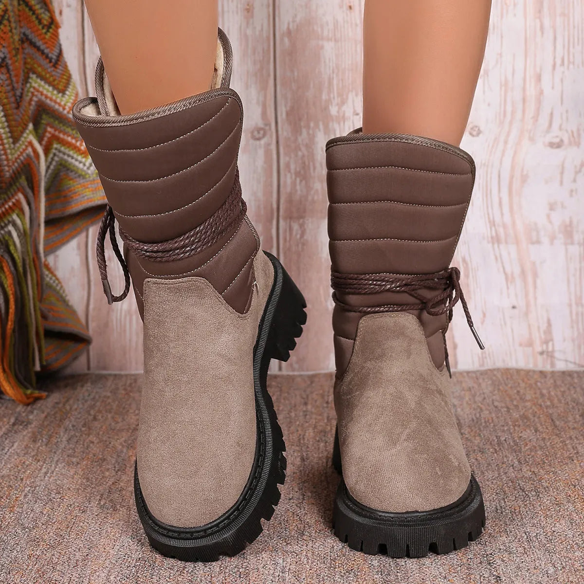A pair of women's chunky heel snow boots in suede with a lace-up front and fleece lining, shown in black.