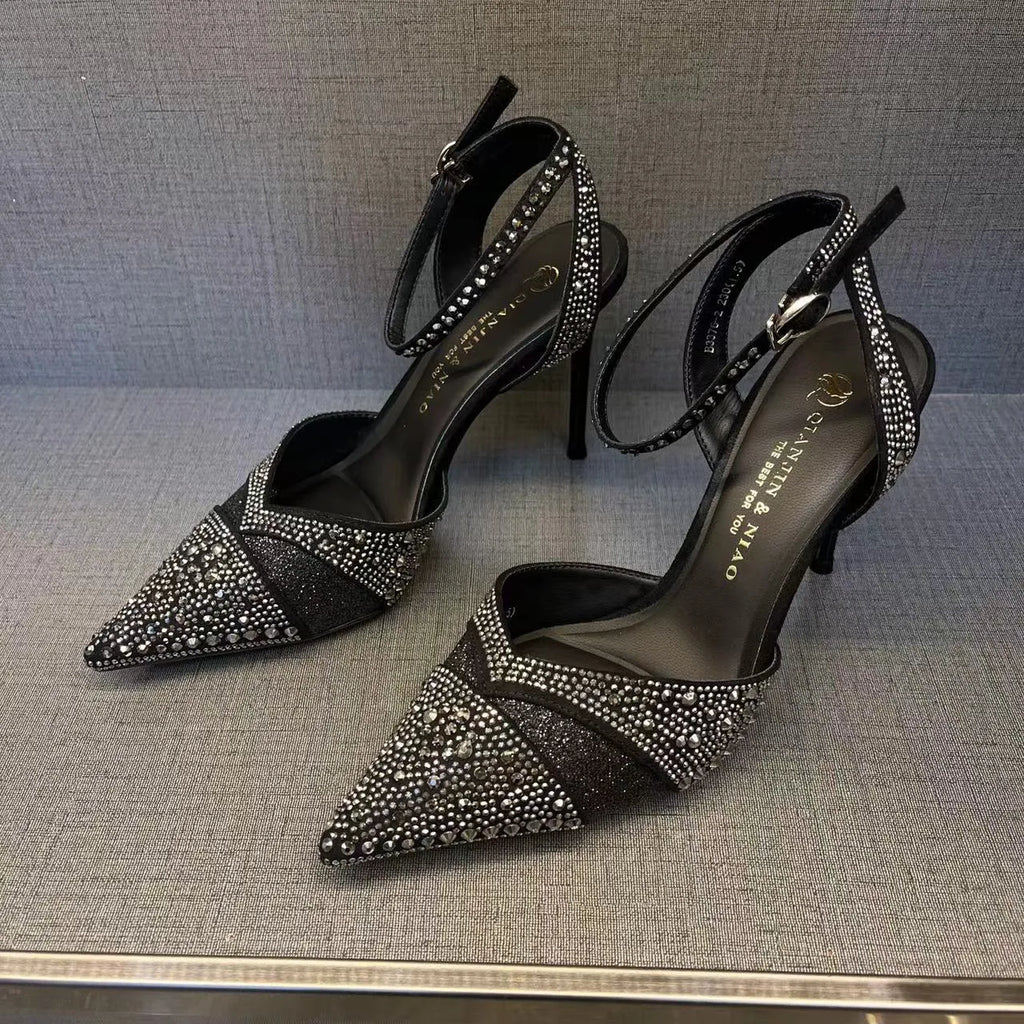 Women's black hollow high heel shoe with red sole and pointed toe, shown next to a silver pair.