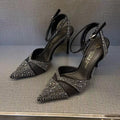 Women's black hollow high heel shoe with red sole and pointed toe, shown next to a silver pair.