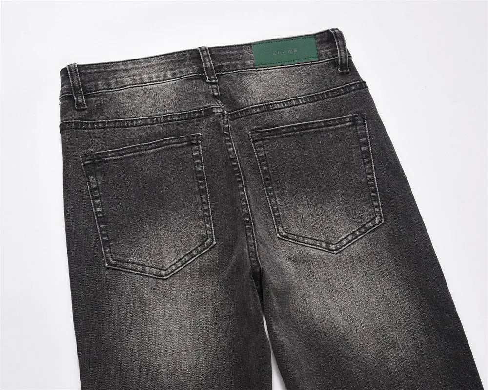 Men's black washed denim jeans on a flat surface showing full leg and pocket details
