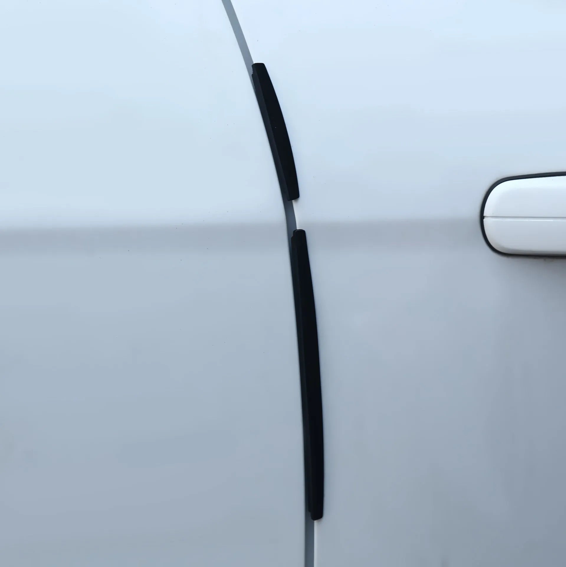 Solid white plastic car door edge protector strip with adhesive backing, shown next to a vehicle door.