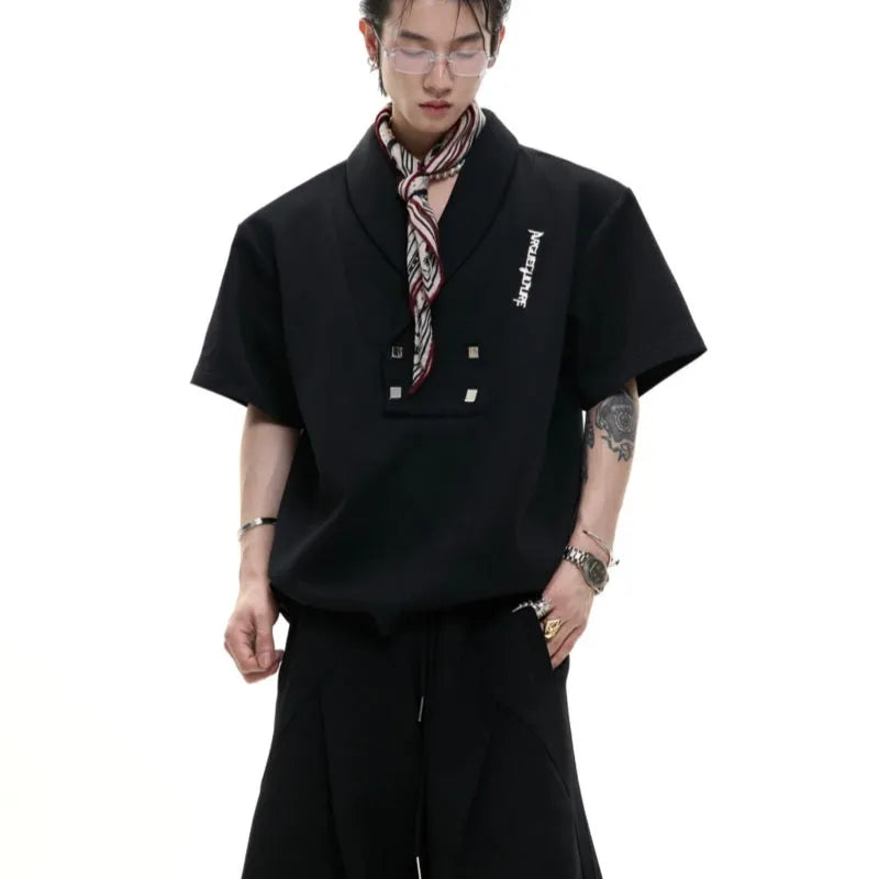 Men's dark grey cotton sports suit with V-neck short-sleeve jacket, padded shoulders, metal embellishments, and matching shorts.