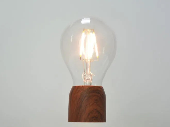 Magnetic levitation floating light bulb hovering above an imitation wood base.