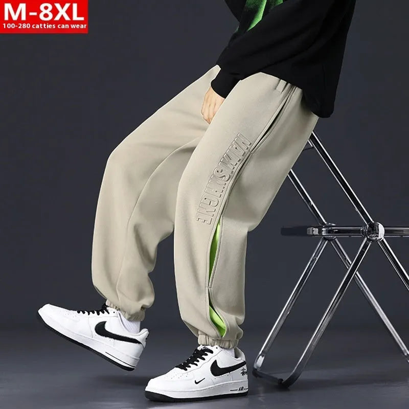 Man wearing loose-fit black trousers with printed stitching detail and a banded ankle cuff.