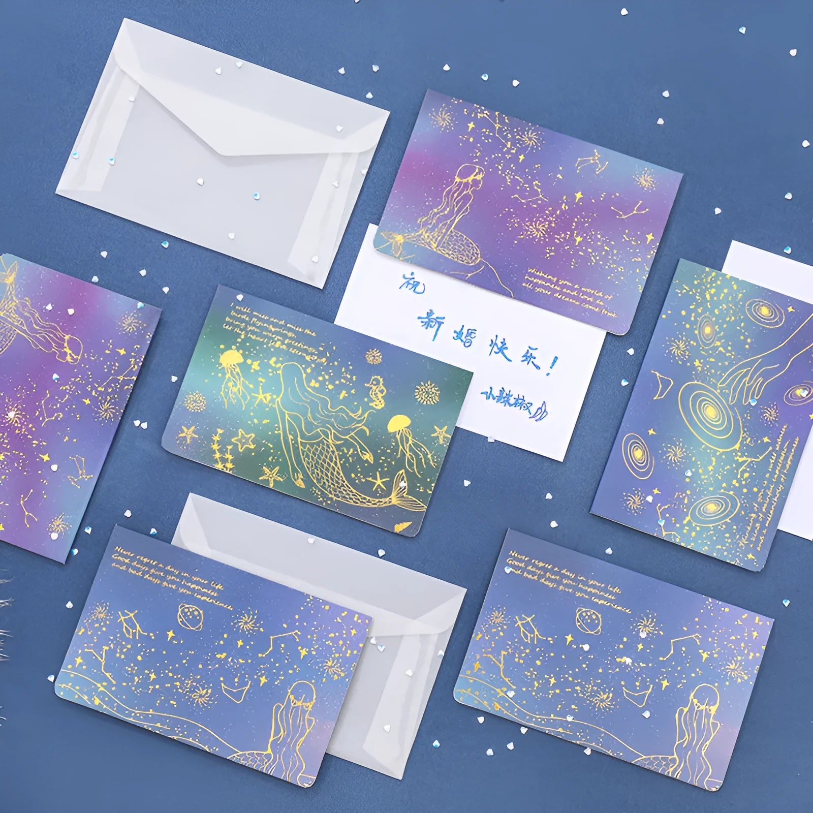 Set of three bronzing mermaid-style folded greeting card envelopes in celestial colourways, 13x8.5cm, on a light background