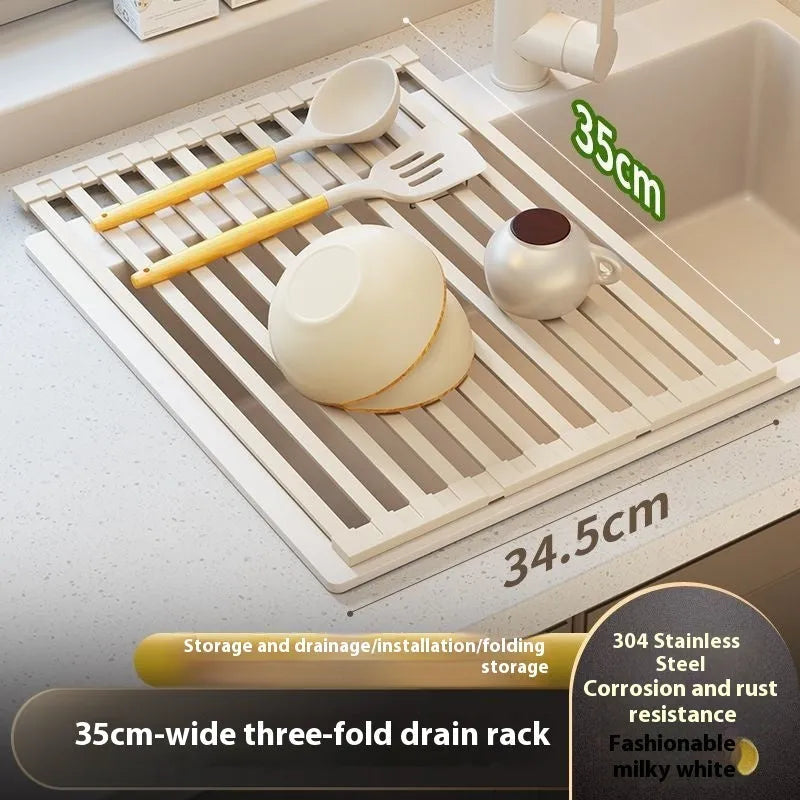 Milky White foldable stainless steel kitchen draining rack shown beside a sink, demonstrating its tri-fold mechanism.