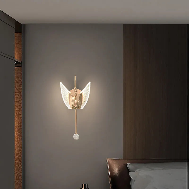 Gold modern swan-shaped bedside wall lamp with an acrylic shade mounted on a wall.